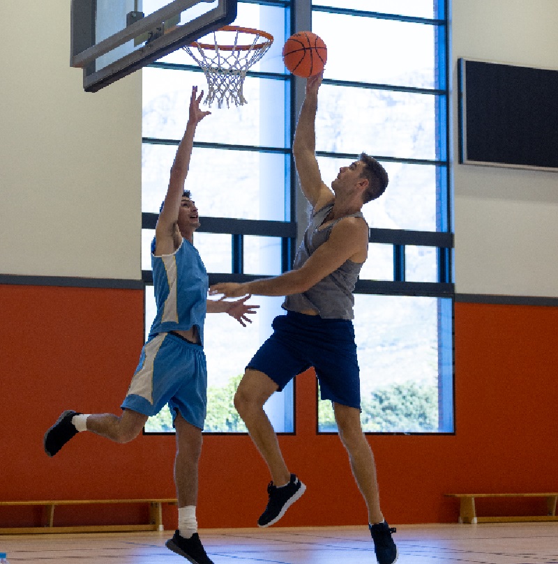 Caucasian male basketball players wearing blue sports clothes and playing basketball at gym. Sport, activity, teamwork and lifestyle, unaltered.